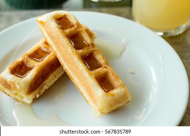 Waffle stick with maple syrup, waffles with syrup on white plate