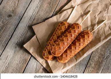 Waffle sticks served on kraft paper on a rustic wooden table. Latest bakery trend. Top view on sweet food.