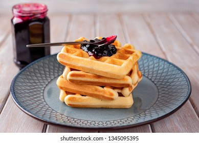 Waffles with blackcurrant jam on a light fot. Breakfast.