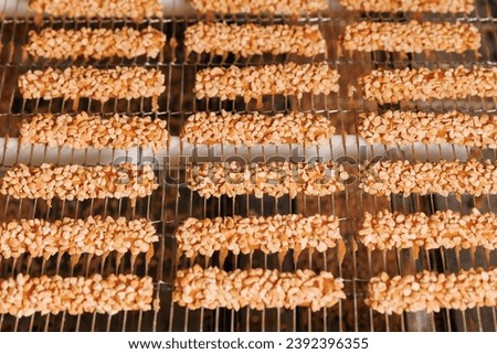 Waffles with nuts are coated with chocolate on conveyor. Food industry Production line of modern sweet candy bakery factory.
