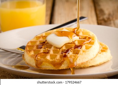 Waffles - This S A Photo Of A Couple Waffles Being Soaked In Syrup. Shot On A Wooden Table With A Shallow Depth Of Field.