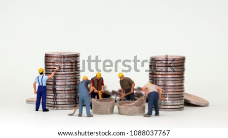 Wage and labor concept. Miniature workers working with piles of coins.