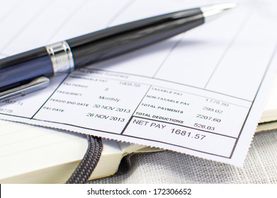 Wage Slip On Notepad With Black Pen In Background 