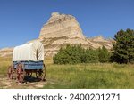 Wagon on display along the Oregon Trail at the entrance of the Mitchell Pass in the vicinity of Sotts Bluff National Monument with Eagle Rock on the right