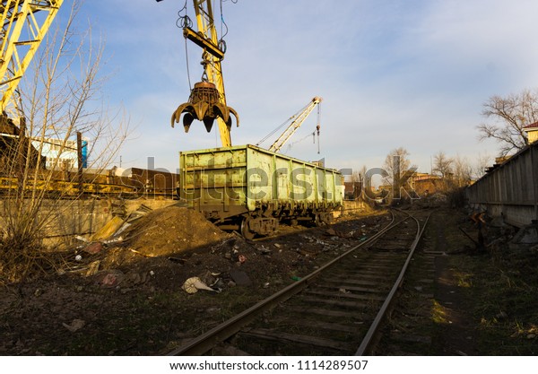 Wagon under a hydraulic crane. Wagon\
under the crane. Train and crane. Heavy\
industry.