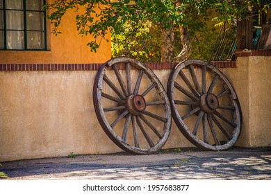 Wagon wheels leaningagainst a fence.