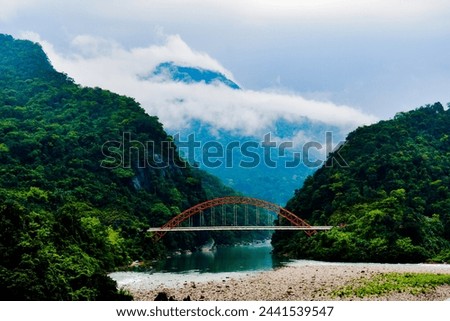 Wahrew Bridge in Meghalaya. With river of green color water with mountains and clouds .