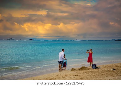 Waikiki, Hawaii - 2-9-2014:  A Family On The Beach At Waikiki, Hawaii.  Mother Is Taking Photo Of Father And Two Sons.