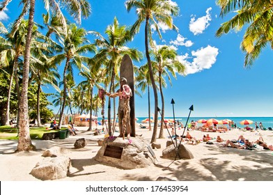 WAIKIKI, HAWAII - SEPTEMBER 7, 2013: Tourists sunbathing and surfing on Waikiki beach in Honolulu, Hawaii. Waikiki white sand beach shoreline is Hawaii's most famous beach.