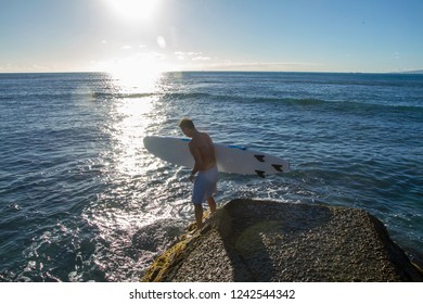 Waikiki, Hawaii / United States - 11/ 19/ 2018 - Surfer About To Jump Into Ocean With Surfboard From A Wharf