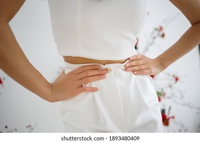 The Waist Of The Bride In A Pantsuit With An Engagement Ring On Her Finger.