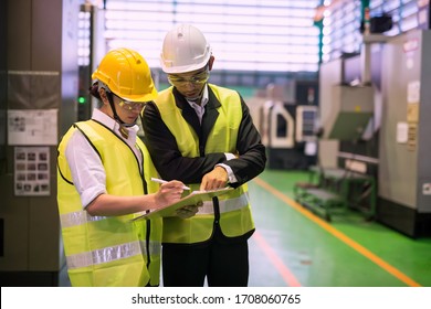 Waist Up Female Inspector Or Manager Discuss Audit Report Of Automated Robot Machine At High Technology Factory Warehouse. Quality Assurance (QA) For Manufacturing Industry.