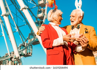 Waist Up Of Happy Senior Couple Standing Near Ferris Wheel And Having Good Day