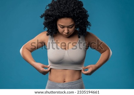 Waist up picture of woman in a bra standing on a blue background