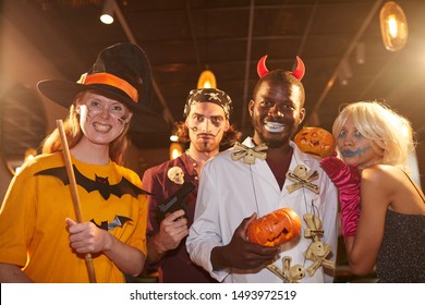 Waist Up Portrait Of Adult People Wearing Halloween Costumes Posing As Witches And Pirates Grimacing At Camera During Party, Shot With Flash