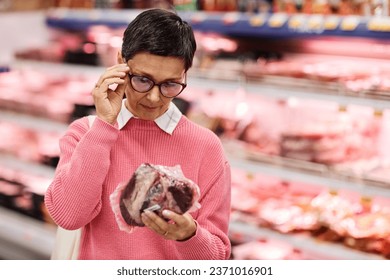 Waist up portrait of adult woman choosing fresh meat shopping for groceries in supermarket, copy space - Powered by Shutterstock