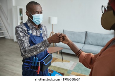 Waist Up Portrait Of African-American Handyman Wearing Mask Bumping Fists With Client As Con Tactless Greeting, Copy Space