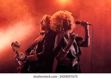 Waist up portrait of band performing on stage in nightclub with Black woman singing to microphone and leaning on guitarist - Powered by Shutterstock