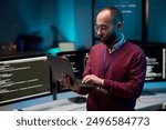 Waist up portrait of bearded adult man holding laptop while standing in cybersecurity office with code lines on screens copy space