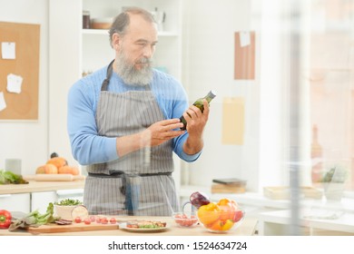 Waist Up Portrait Of Bearded Senior Man Cooking Dinner At Home And Reading Nutrition Label On Olive Oil, Copy Space