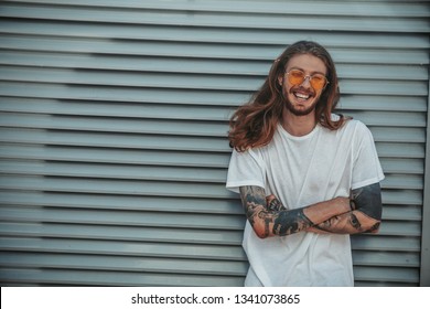 Waist up portrait of bearded young man with tattoos on his hands looking at camera and smiling. Copy space in left side - Powered by Shutterstock