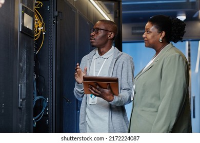 Waist Up Portrait Of Black IT Engineer With Female Assistant In Server Room Inspecting Network Systems