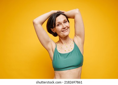 Waist Up Portrait Of Carefree Adult Woman With Flowers On Skin Wearing Underwear Against Vibrant Yellow Background, Copy Space