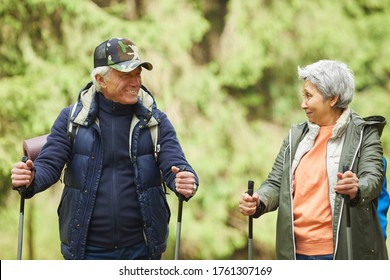 Waist Up Portrait Of Cheerful Senior Couple Enjoying Nordic Walking With Poles During Hike In Forest