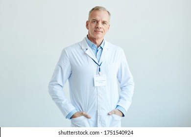 Waist Up Portrait Of Confident Mature Doctor Wearing Lab Coat And Looking At Camera While Standing Against White Wall In Clinic, Copy Space