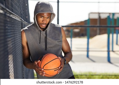 Waist up portrait of contemporary African-American man holding basketball ball looking at camera while posing in sports court outdoors, copy space - Powered by Shutterstock