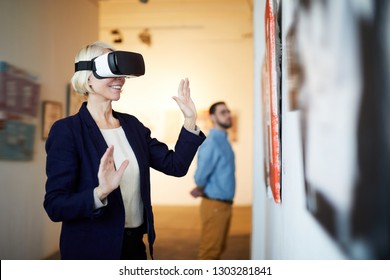 Waist up portrait of contemporary smiling woman wearing VR headset in art gallery, copy space