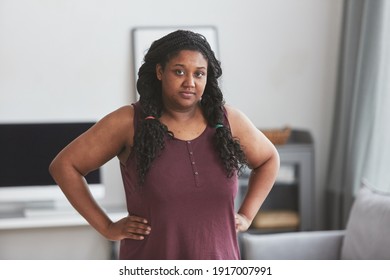 Waist Up Portrait Of Curvy African American Woman Looking At Camera While Standing With Hands On Hips In Minimal Home Interior, Copy Space