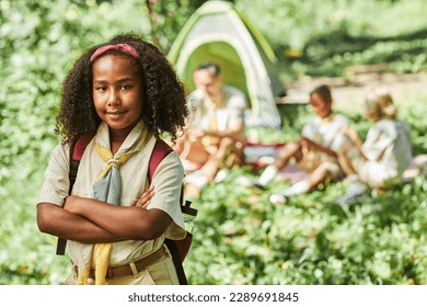 Waist up portrait of cute black girl scout looking at camera while camping with school group, copy space - Powered by Shutterstock