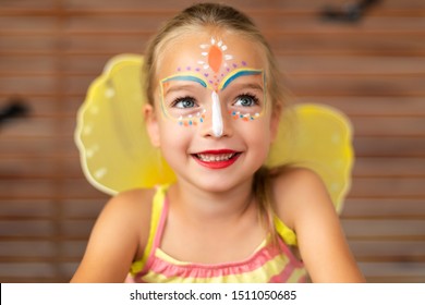 Waist Up Portrait Of Cute Preschooler With DIY Face Paint Wearing A Butterfly Halloween Or Carnival Costume.