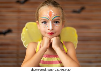 Waist Up Portrait Of Cute Preschooler With DIY Face Paint Wearing A Butterfly Halloween Or Carnival Costume.