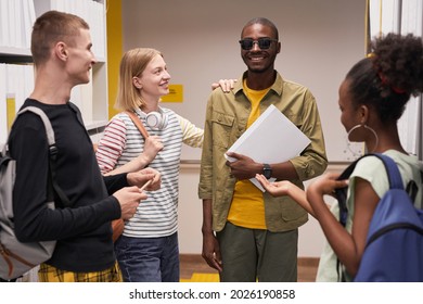 Waist up portrait of diverse group of students chatting with smiling blind man