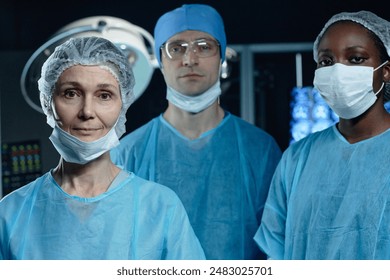 Waist up portrait of diverse medical team in operating room looking at camera with focus on mature woman surgeon in foreground, copy space - Powered by Shutterstock