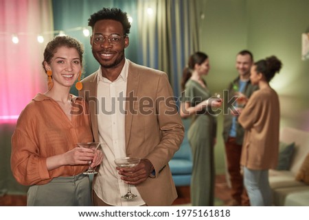 Waist up portrait of elegant young couple looking at camera while enjoying party at home, copy space