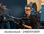 Waist up portrait of female director looking at camera screen while leading video production on set