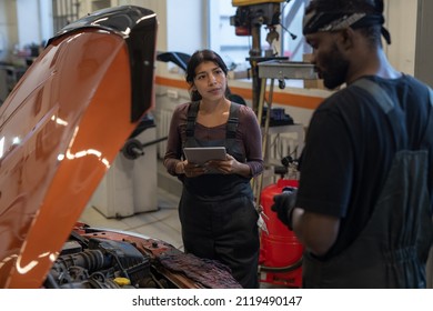 Waist up portrait of female mechanic using digital tablet while inspecting car in auto repair workshop - Powered by Shutterstock