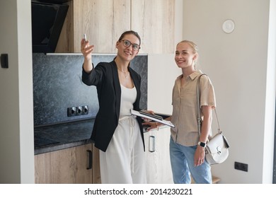 Waist Up Portrait Of Female Real Estate Agent Giving Apartment Tour To Young Woman Buying New House