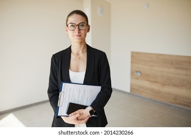 Waist Up Portrait Of Female Real Estate Agent Smiling At Camera While Standing In Empty House, Copy Space