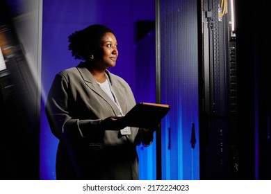 Waist Up Portrait Of Female System Admin Using Tablet In Server Room Lit By Neon Light, Copy Space