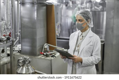 Porträt der Arbeitnehmerin, die eine Maske trägt und digitale Tablette bei der Qualitätskontrolle in der Lebensmittelfabrik hält, Kopienraum