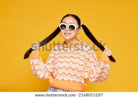 Waist up portrait of funky teenage girl with pigtails over colored yellow background, copy space