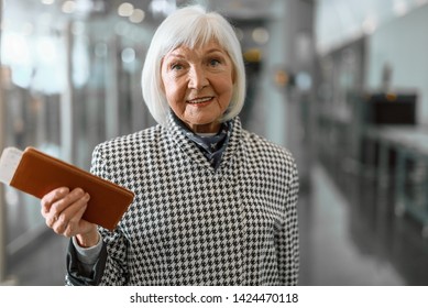 Waist Up Portrait Of Happy Mature Lady Check In Ticket At Hall While Holding Coffee In Hand. Copy Space In Right Side