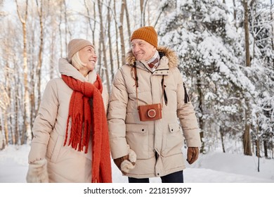 Waist up portrait of happy senior couple enjoying walk in winter forest and holding hands - Shutterstock ID 2218159397