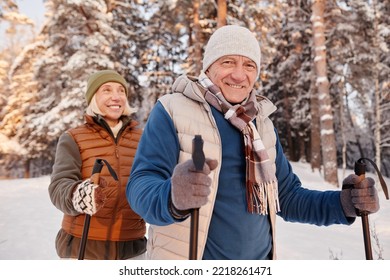 Waist up portrait of happy senior couple walking with poles in winter forest and smiling at camera - Shutterstock ID 2218261471
