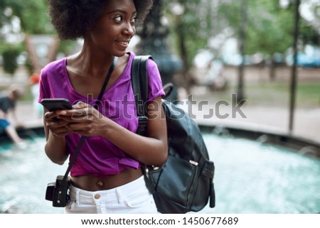 Similar – Frau mit Afro-Haaren auf der Straße, die ein Smartphone hält.