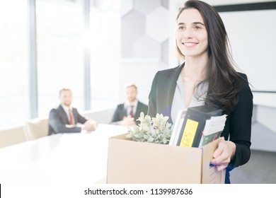 Waist up portrait of happy young businesswoman holding box of personal belongings  leaving office after quitting job, copy space